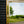 The corner detail of a bespoke mirror made using an antique gold frame with a Venetian mirror inlay. The central mirror has a bevel and is reflecting the East Sussex countryside. This traditional style mirror is leaning against a workshop roller door. 