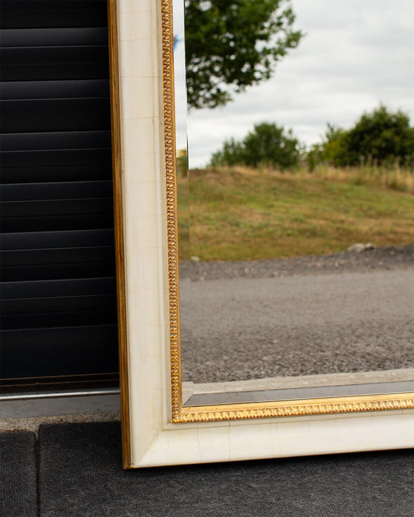 A corner detail of a bevelled mirror framed using an aged cracked gesso finish with antique gold detailing. 