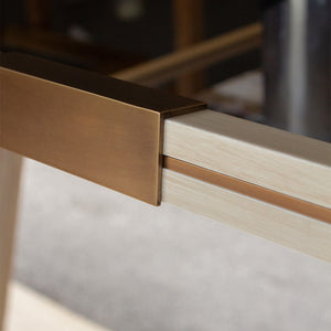 A close up look at an antique brass clip and inlay along the frame of a bespoke mirror finished in distressed white. 