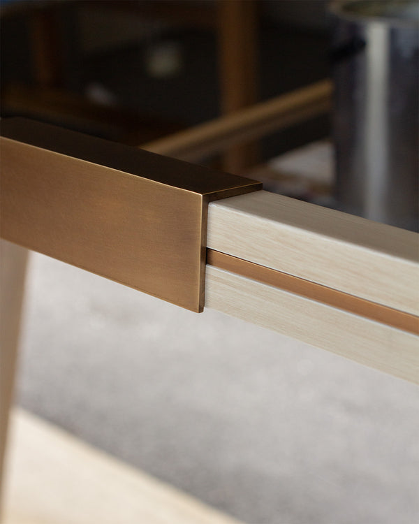 A close up look at an antique brass clip and inlay along the frame of a bespoke mirror finished in distressed white. 
