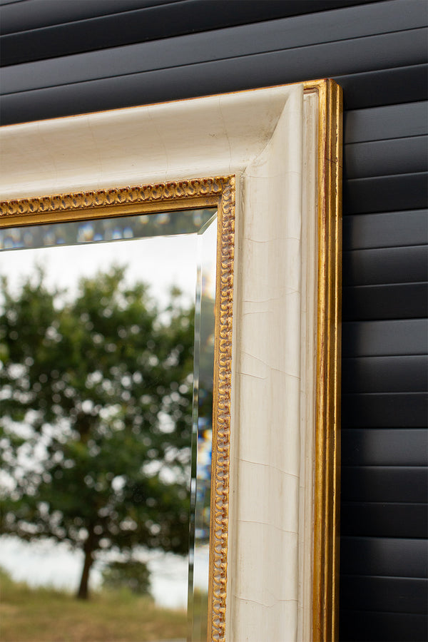 Corner detail of a bevelled mirror framed using an aged cracked gesso finish with antique gold detailing. 
