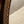 A close-up photo of an oval shaped mirror. The frame is finished in an imitation brass and a bobbin detail runs along the inside of the frame. The mirror glass is lightly antiqued with heavier antiquing along the edges. 