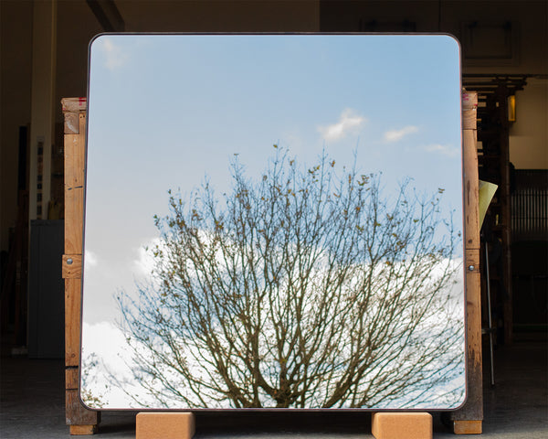 A bespoke square mirror with radial corners and a thin 6mm wide bronze frame running along the outside of the mirror glass. 