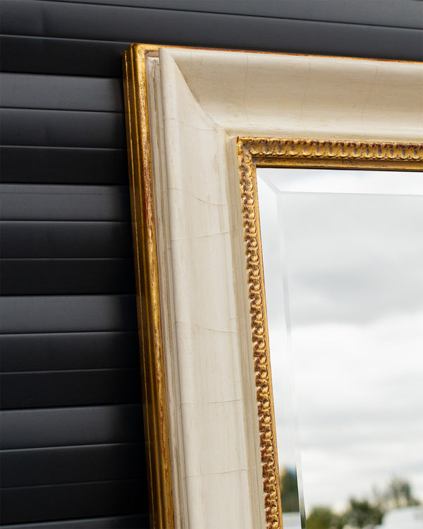 Corner detail of a bevelled mirror framed using an aged cracked gesso finish with antique gold detailing. 